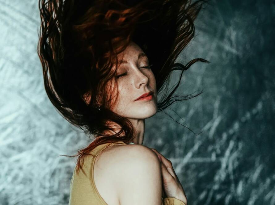 Mulher de cabelos longos avermelhados em movimento, fotografia editorial ilustrativa