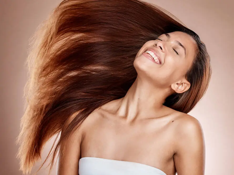 Mulher sorrindo com cabelo castanho longo e liso em movimento
