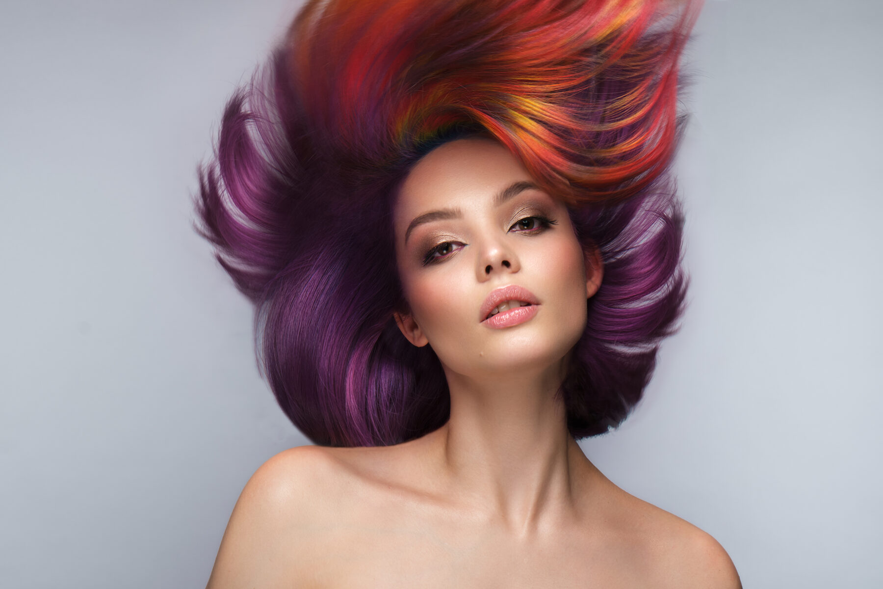 Retrato editorial de mulher com cabelo fantasia violeta, vermelho e laranja